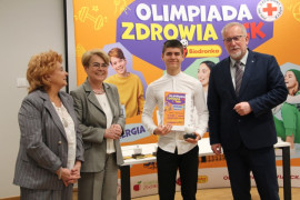 Cztery osoby: dwie kobiety, mężczyzna i chłopiec stoją obok siebie. Chłopiec trzyma w ręku dyplom 
