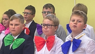 Dzieci stoją obok siebie. Mają kolorowe muchy 