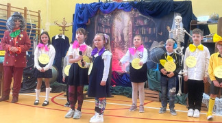 Dzieci w kolorowych strojach podczas występu na szkolnej akademii 