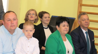 Grupa osób. Osoby siedzą obok siebie na ławce
