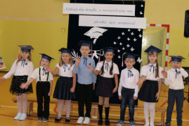Grupa uczniów w granatowych biretach na głowie 