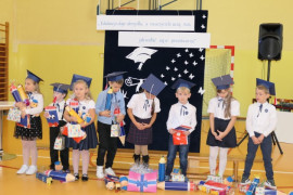 Grupa dzieci w granatowych biretach obok siebie