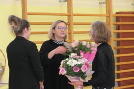 Trzy kobiety. Moment wręczania jednej z nich bukietu kwiatów