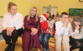 Grupa osób: dorośli i dzieci siedzą obok siebie