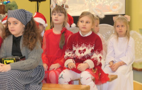 Uczniowie w kolorowych strojach siedzą obok siebie