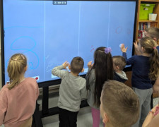 Dzieci stoją przy monitorze interaktywnym 