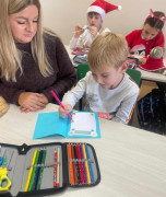 Troje dzieci i kobieta. Dzieci przygotowują kartki świąteczne 
