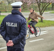 Chłopiec jedzie a rowerze. Jeździe przygląda się policjant. Wydarzenie dotyczy konkursu w ruch drogowym 