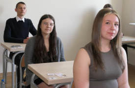 Uczniowie siedzą w szkolnych ławkach