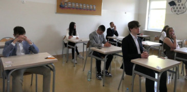 Uczniowie siedzą w szkolnych ławkach