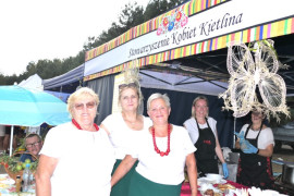 Stoisko wystawiennicze i kobiety stojące przed nim 