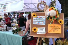 Stoisko wystawiennicze i tablica informacyjna stojąca przed nim 