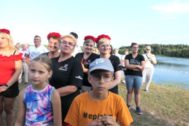 Grupa osób: dorośli i dzieci nad zalewem 